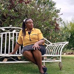 a woman sitting on a white bench in the grass