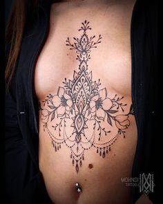 a woman's stomach with an intricate tattoo design on the side and breast area