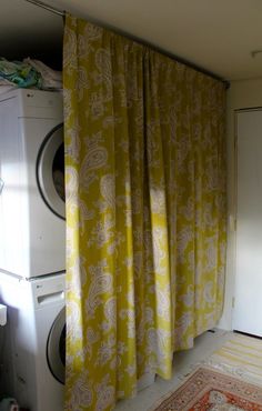 a washer and dryer in a room with yellow curtains