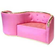 a pink couch with gold trimmings on the arms and back, sitting in front of a white background