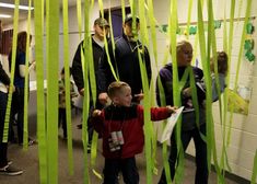 a group of people standing next to each other in a room with green streamers hanging from the ceiling