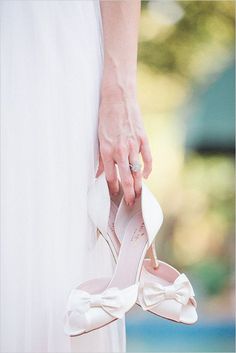 the bride's wedding shoes are being held up by her mother, who is wearing a white dress