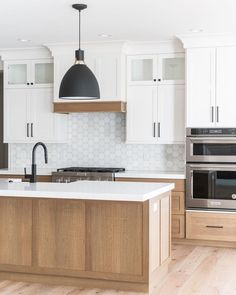 a kitchen with an island, stove and oven in it's center island is surrounded by white cabinetry