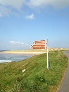 a sign on the side of a road pointing to two different directions with water in the background