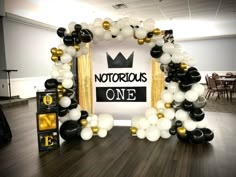 an arch made out of balloons and black and white balloons with a crown on top