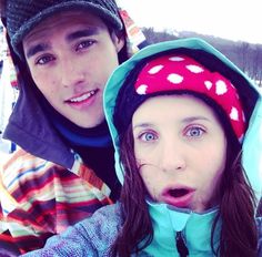 two people standing next to each other with snow on their heads and trees in the background