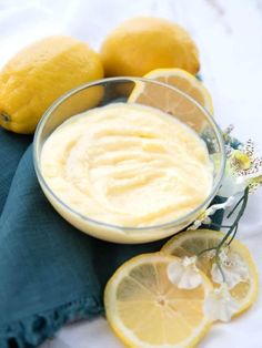 a bowl of lemon custard next to sliced lemons on a blue towel