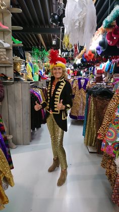 a woman standing in front of a store filled with lots of colorful clothing and decorations