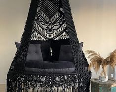 a black hammock hanging from the ceiling with pillows on it's sides