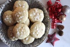 a plate full of cookies with white sprinkles on them next to christmas decorations