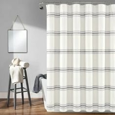 a white shower curtain in a bathroom with wood floors and gray walls, along with a mirror on the wall