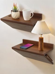 two wooden shelves with one holding a cell phone and the other displaying a lamp