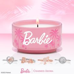 a pink candle with the word barbie written on it and some other items around it