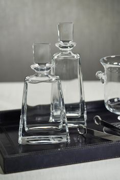 three glass vases sitting on top of a black tray next to scissors and other items