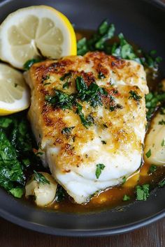 a plate with fish, lemons and greens on the side for garnish