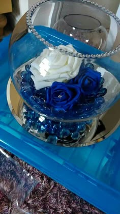 a clear bowl with blue and white flowers in it sitting on a glass table top