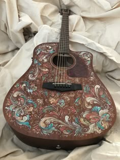 an old wooden guitar with floral designs on it