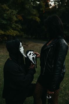 two people standing in the grass with one wearing a mask and the other holding a glove