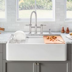 a white kitchen sink with cutting board and utensils on the counter top next to it