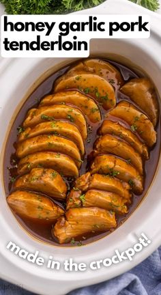 a white bowl filled with meat covered in gravy and garnished with parsley