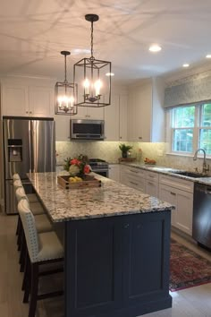 a large kitchen with an island in the middle and lots of lights hanging from the ceiling