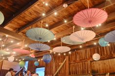 many colorful umbrellas hanging from the ceiling in a room with wood paneled walls