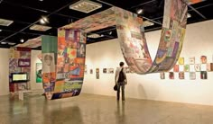 a woman is looking at art on display in an art gallery with multiple banners hanging from the ceiling