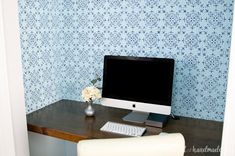 a desktop computer sitting on top of a wooden desk next to a vase with flowers