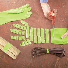 someone cutting up pieces of green paper on a wooden table with scissors and other items