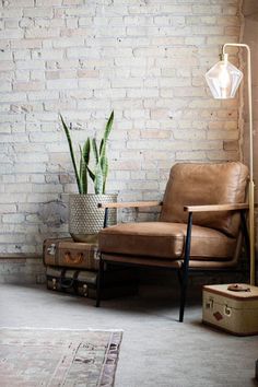 a brown chair sitting next to a white brick wall with a potted plant on top of it