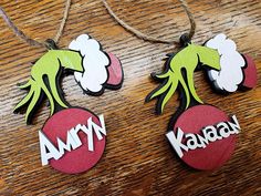 two wooden ornaments with the words, army and kansan hanging from strings on a table