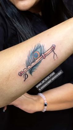 a woman with a tattoo on her arm has a feather and an arrow in it