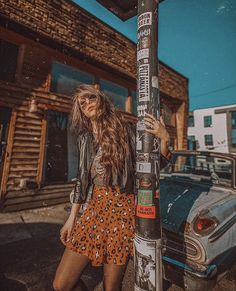 a woman standing next to a pole with stickers on it