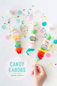 candy kabobs are being held by someone's hand