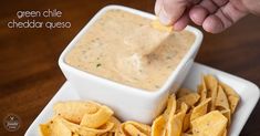 a person dipping tortilla chips into a white bowl