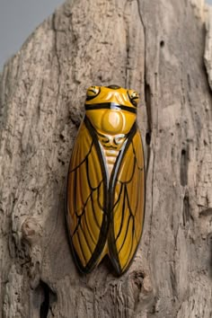 a yellow and black insect sitting on top of a tree