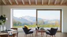 a living room filled with furniture next to a large glass window covered in snow capped mountains