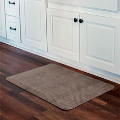 a kitchen with white cabinets and wood floors