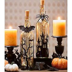 three bottles with halloween decorations and candles on a table