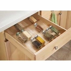 an open drawer in a kitchen with spices and seasonings on the bottom shelf,