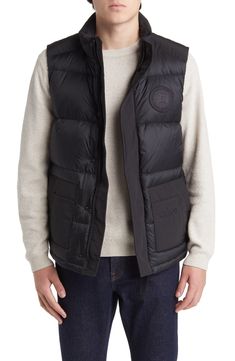 Weather it all in comfort and warmth wearing this vest featuring dual-entry pockets, a webbing grab strap at the upper back and 625-fill-power down insulation. 28" length (size Medium) Storm placket Stand collar Durable water-repellent (DWR) finish Lined, with 625-fill-power down 100% polyamide with 84% polyester, 16% cotton contrast Dry clean Made in Canada Winter Utility Nylon Vest, Utility Nylon Vest Outerwear, Functional Nylon Vest Outerwear, Sleeveless Black Down Outerwear, Down Vest With Padded Collar, Sleeveless Down Vest With Padded Collar, Black Utility Vest For Winter, Winter Black Vest With Side Pockets, Black Winter Vest With Side Pockets