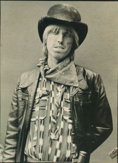 an old black and white photo of a man wearing a leather jacket with a hat on his head