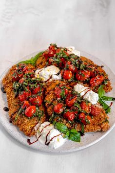 a white plate topped with meat covered in sauce and tomatoes on top of lettuce