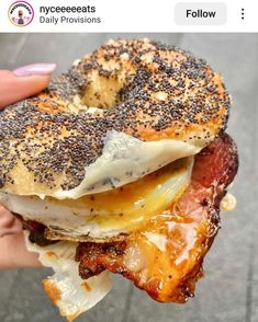 a person holding a bagel with bacon and egg