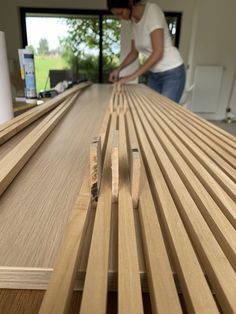 a woman standing over a wooden table with wood slats on the top and bottom