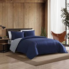 a bed in a room with wood paneling and blue comforter on the floor