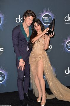 a man and woman posing for the camera at an awards event with their award in hand