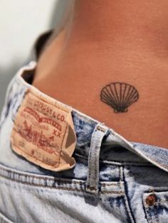 a close up of a person's stomach with a shell tattoo on her lower back