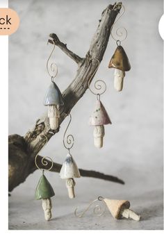 a group of small ceramic mushrooms hanging from a tree branch with hooks on it's sides