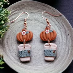 two small pumpkins are hanging from the earwires of some kind of earrings